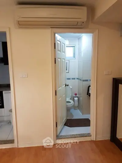 Compact bathroom with air conditioning unit above door in cozy apartment setting.