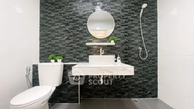 Modern bathroom with sleek black tile wall and round mirror