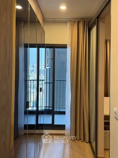 Modern apartment with mirrored wardrobe and balcony view of city skyline.