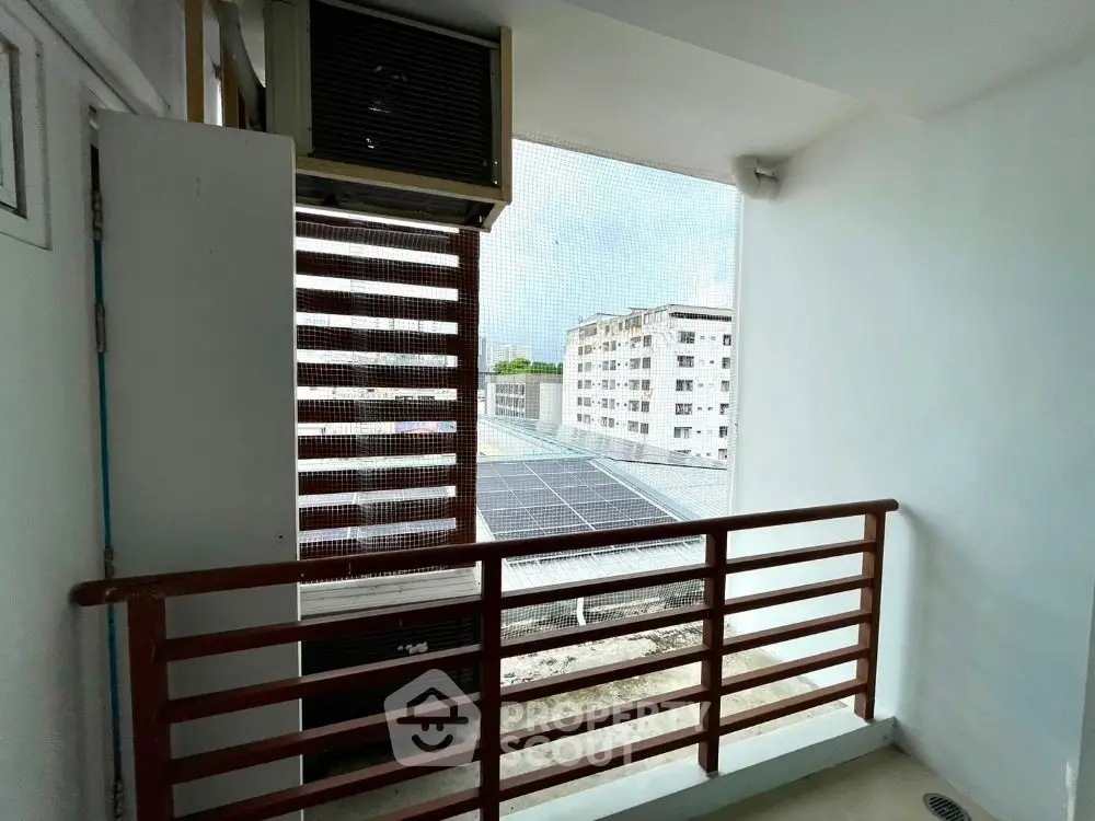 Cozy balcony with city view and air conditioning unit, perfect for relaxation.
