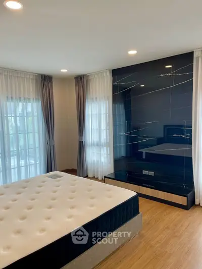 Spacious bedroom with elegant decor and large windows for natural light.