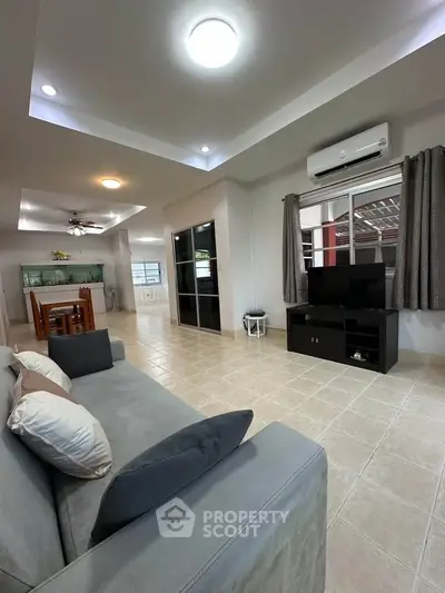 Spacious living room with modern decor and open layout, featuring a cozy sofa and entertainment center.