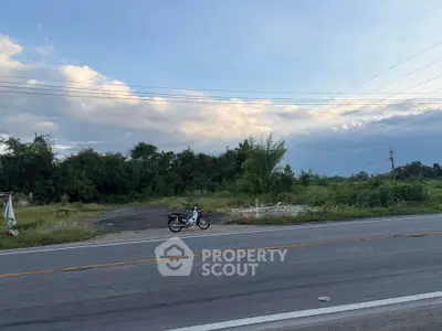 Prime roadside land plot with lush greenery, ideal for development opportunities.