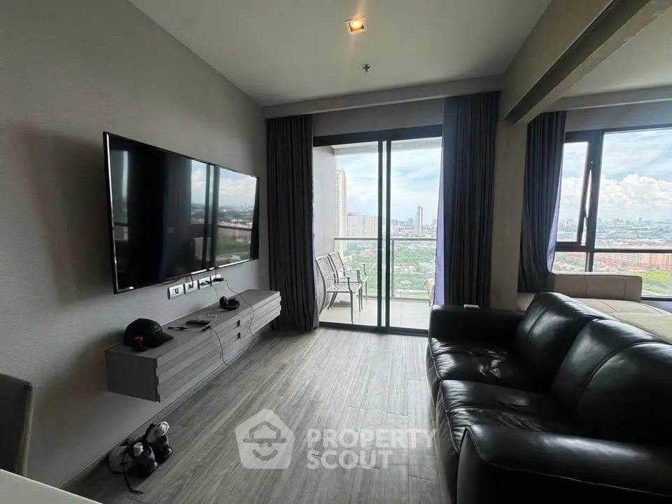 Modern living room with large TV and balcony view in high-rise apartment.
