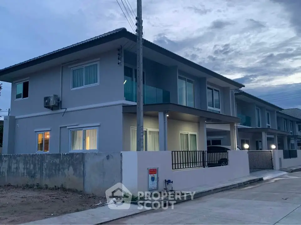 Modern two-story house with sleek design and spacious balcony at dusk.