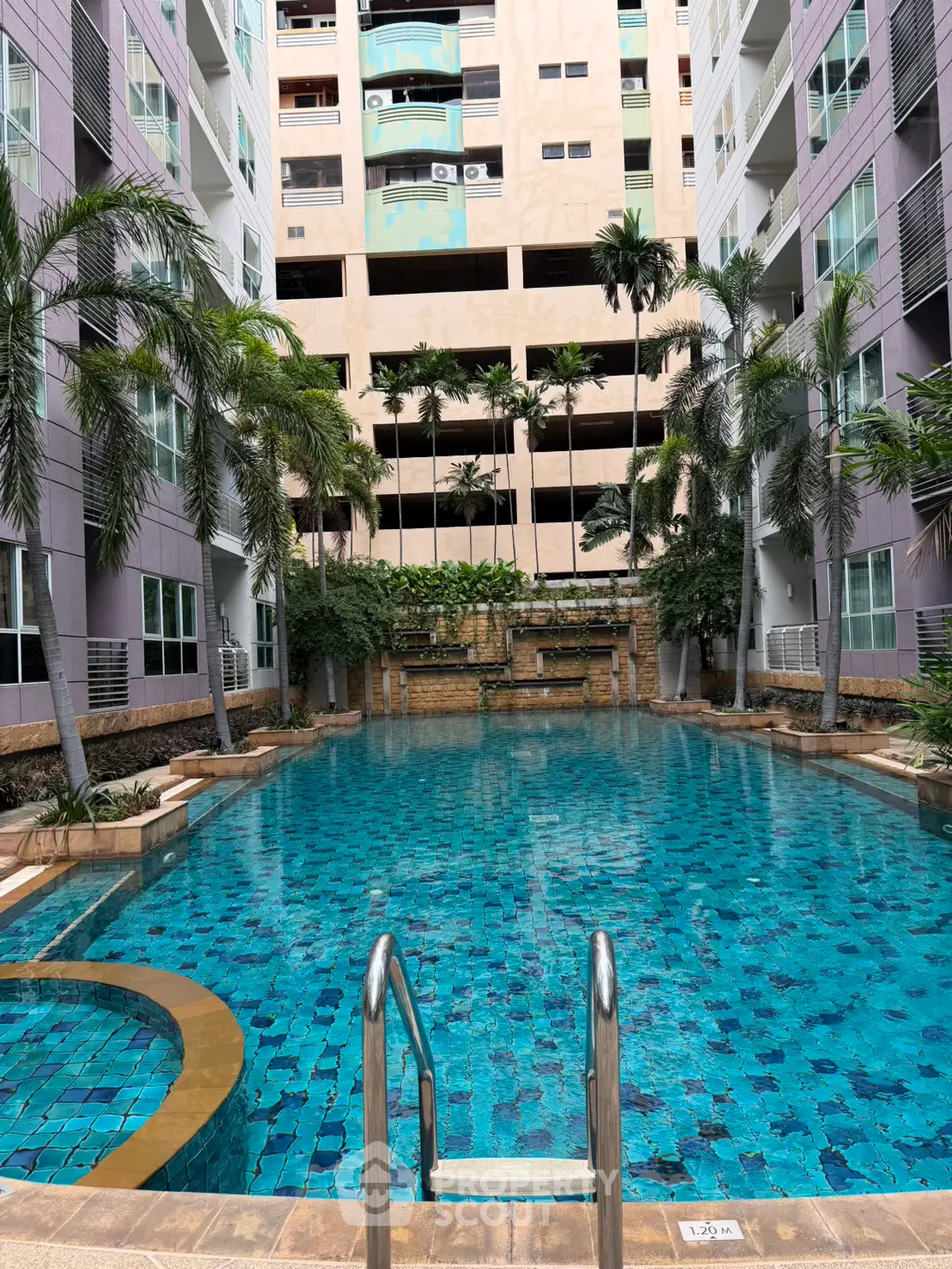 Luxurious apartment complex with a stunning outdoor pool surrounded by palm trees and modern architecture.