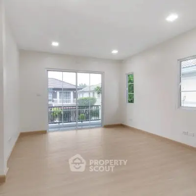 Spacious empty room with wooden flooring and balcony view, perfect for customization.