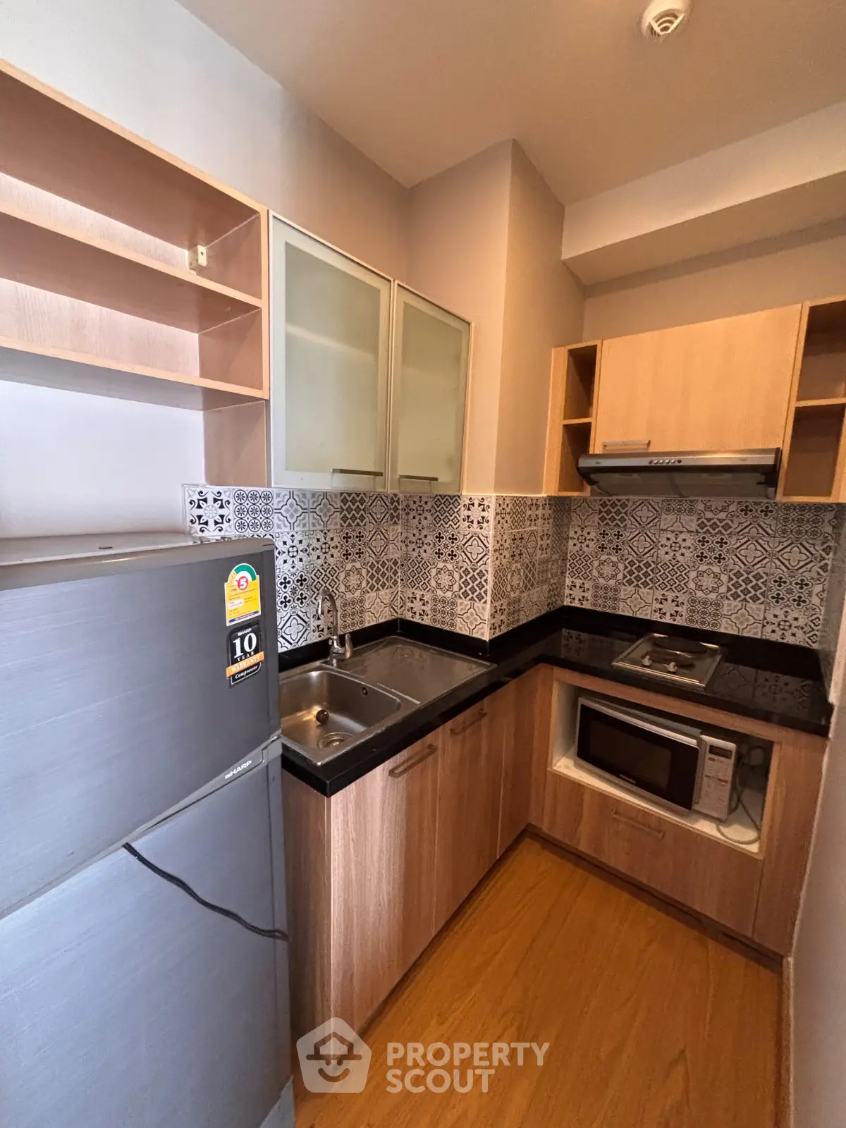 Modern compact kitchen with stylish backsplash and built-in appliances in cozy apartment.