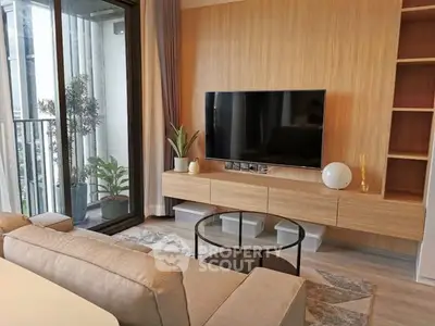 Modern living room with sleek TV setup and balcony view, featuring stylish furniture and natural light.