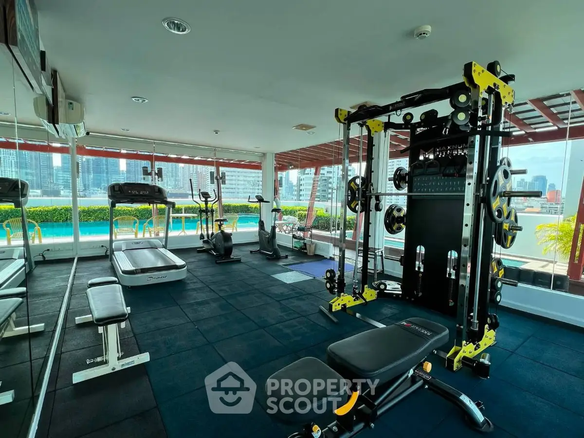 Modern gym with city view and pool access in luxury residential building.