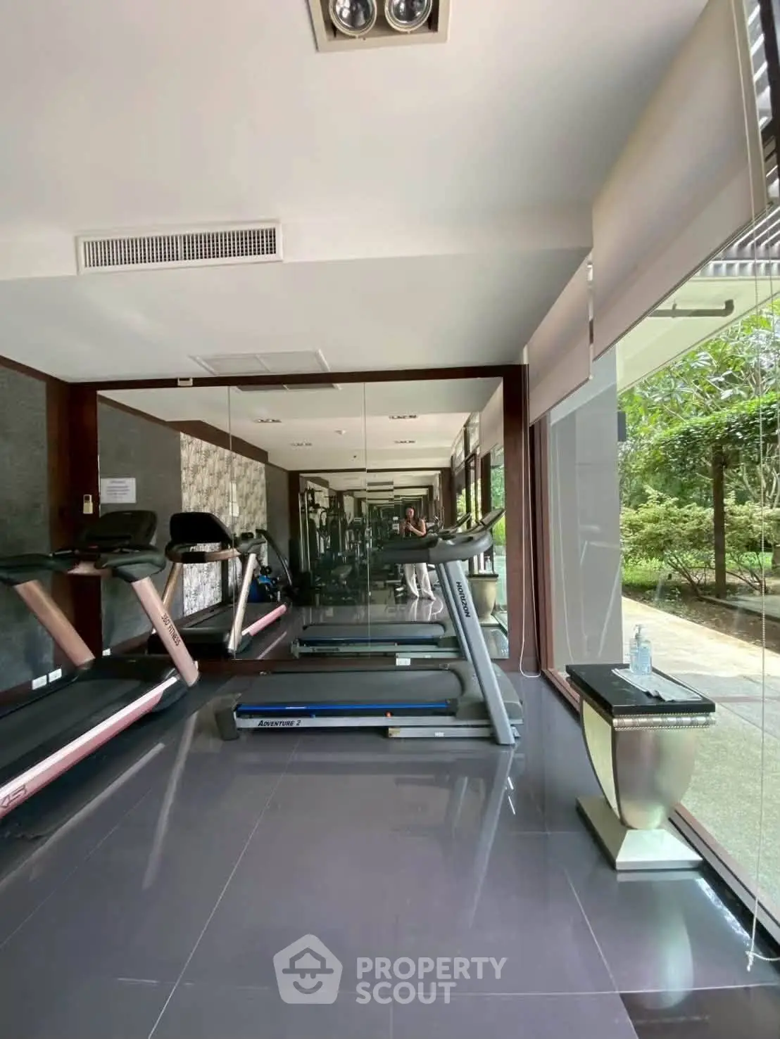 Modern gym with treadmills and large windows overlooking greenery, perfect for fitness enthusiasts.