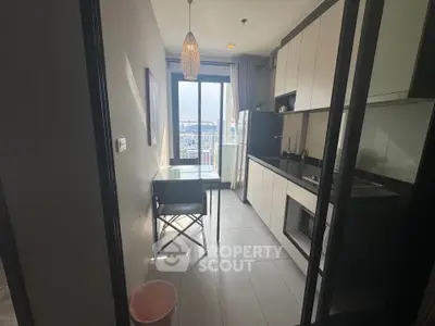 Modern kitchen with sleek cabinets and city view from window, featuring a cozy dining area.