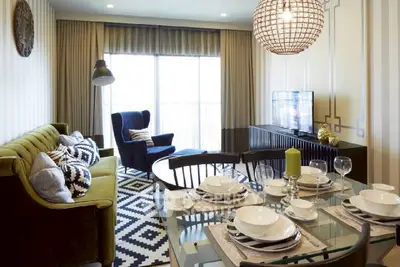 Stylish living room with modern decor and dining area, featuring elegant lighting and cozy seating.