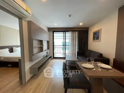 Modern open-plan living room with dining area and balcony access in stylish apartment.