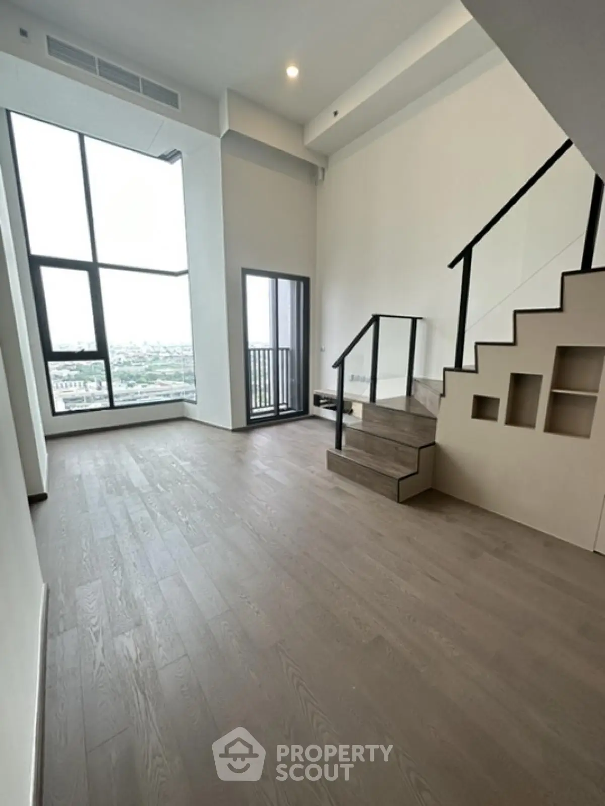Spacious modern living room with high ceilings and large windows offering stunning city views.