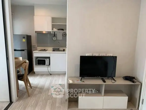 Modern compact living space with kitchen and entertainment area, featuring sleek appliances and minimalist design.