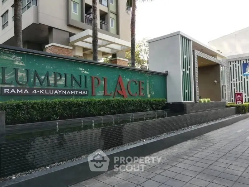 Modern condominium entrance with sleek design and lush greenery at Lumpini Place.