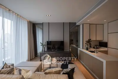 Modern living room with open kitchen, stylish decor, and large windows for natural light.