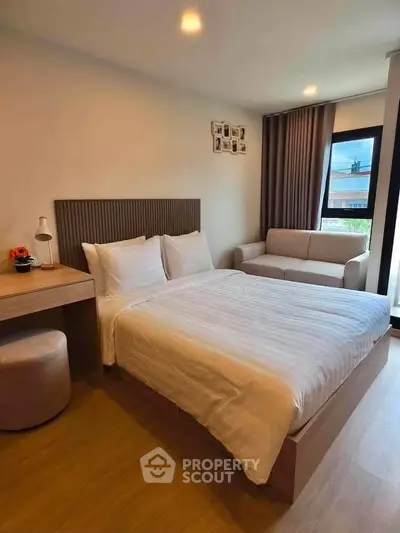 Modern bedroom with cozy bed, stylish decor, and natural light from large window.