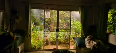 Cozy living room with sliding glass doors opening to lush garden view, perfect for relaxation.