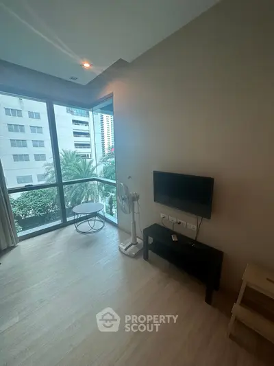 Modern living room with large windows and city view, featuring minimalist furniture and natural light.