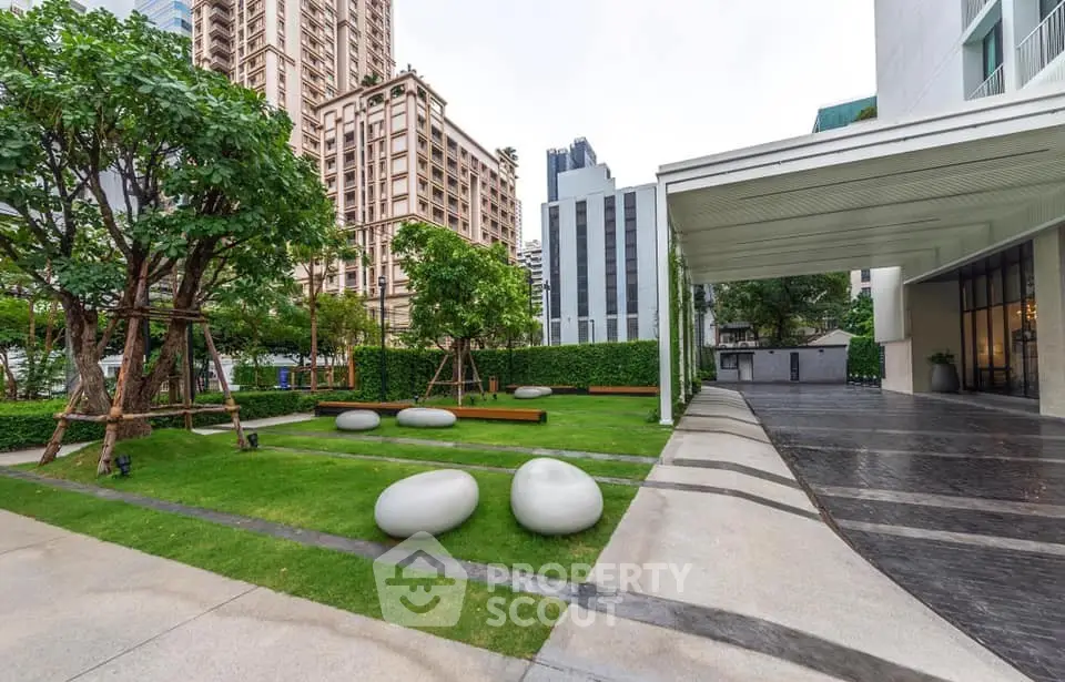 Modern building exterior with landscaped garden and unique stone seating in urban setting.