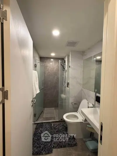 Modern bathroom with glass shower, sleek fixtures, and elegant tile design.