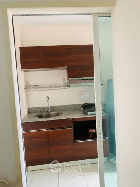 Compact kitchen with sleek wooden cabinets and granite countertop in modern apartment.