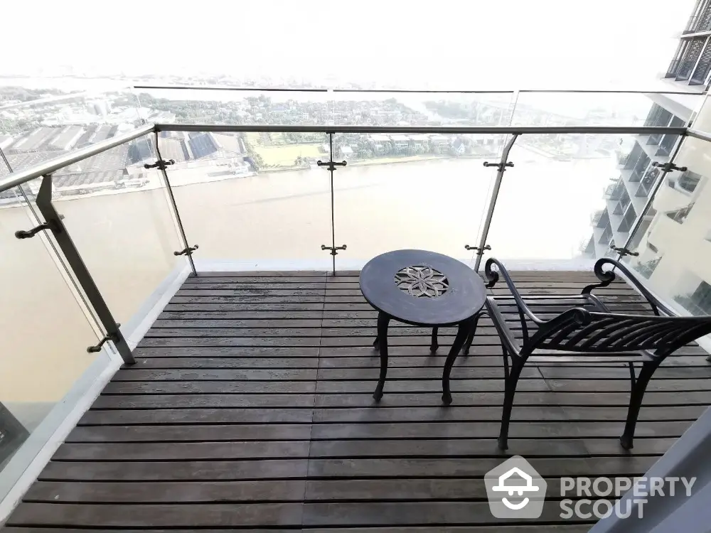 Stunning balcony with river view and elegant outdoor seating in modern high-rise apartment.