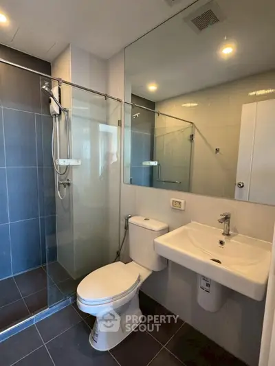 Modern bathroom with glass shower and sleek fixtures in contemporary apartment.