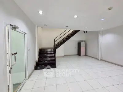 Spacious modern interior with sleek staircase and tiled flooring, ideal for versatile living or office space.