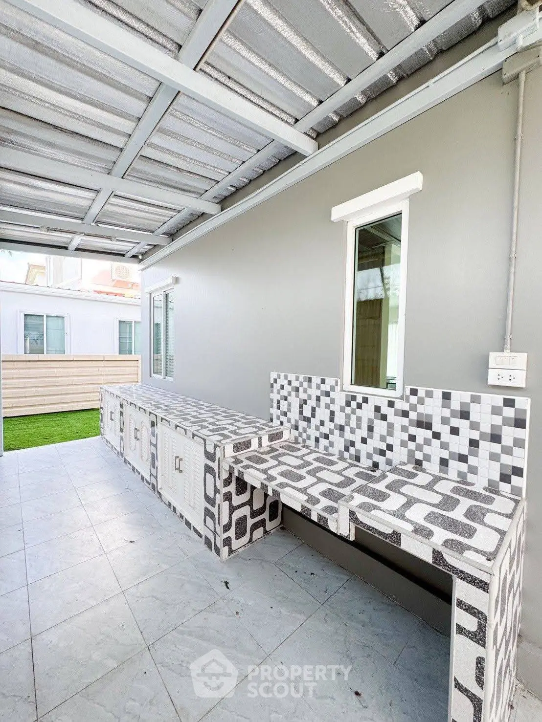 Modern outdoor kitchen with tiled countertops and covered roof, perfect for entertaining.