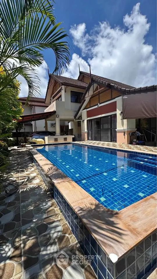 Luxurious villa with stunning pool and tropical landscaping under a clear blue sky.