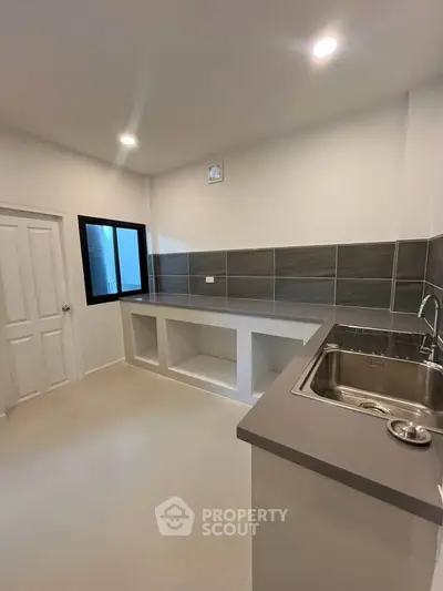 Modern kitchen with sleek countertops and built-in sink, featuring a minimalist design and ample storage space.