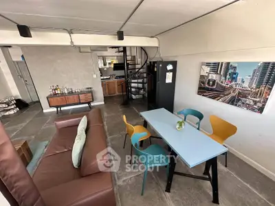 Stylish open-plan living room with modern furniture and spiral staircase in urban apartment.