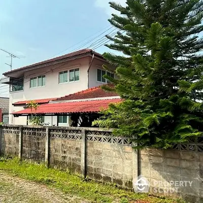 Charming two-story residence surrounded by lush greenery with a spacious balcony and a secure perimeter wall, offering privacy and tranquility.