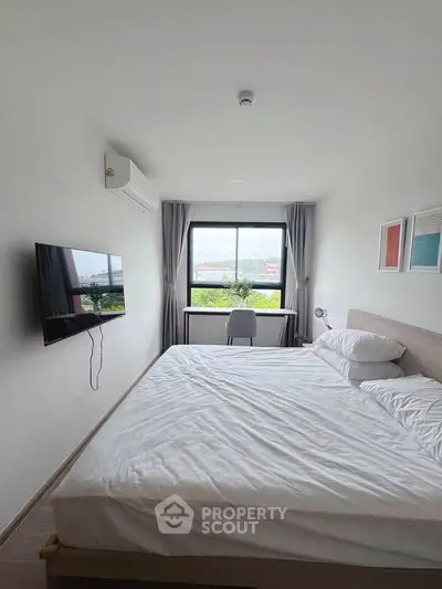 Modern bedroom with large window and wall-mounted TV, offering a bright and airy atmosphere.