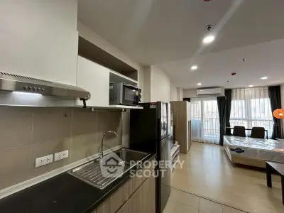 Modern open-layout apartment with kitchen and living area, featuring sleek appliances and ample natural light.