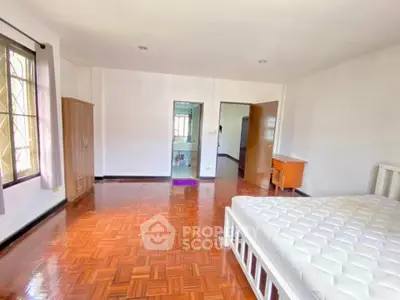 Spacious bedroom with wooden flooring and natural light
