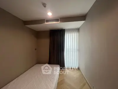 Minimalist bedroom with natural light and modern design, featuring a single bed and elegant curtains.