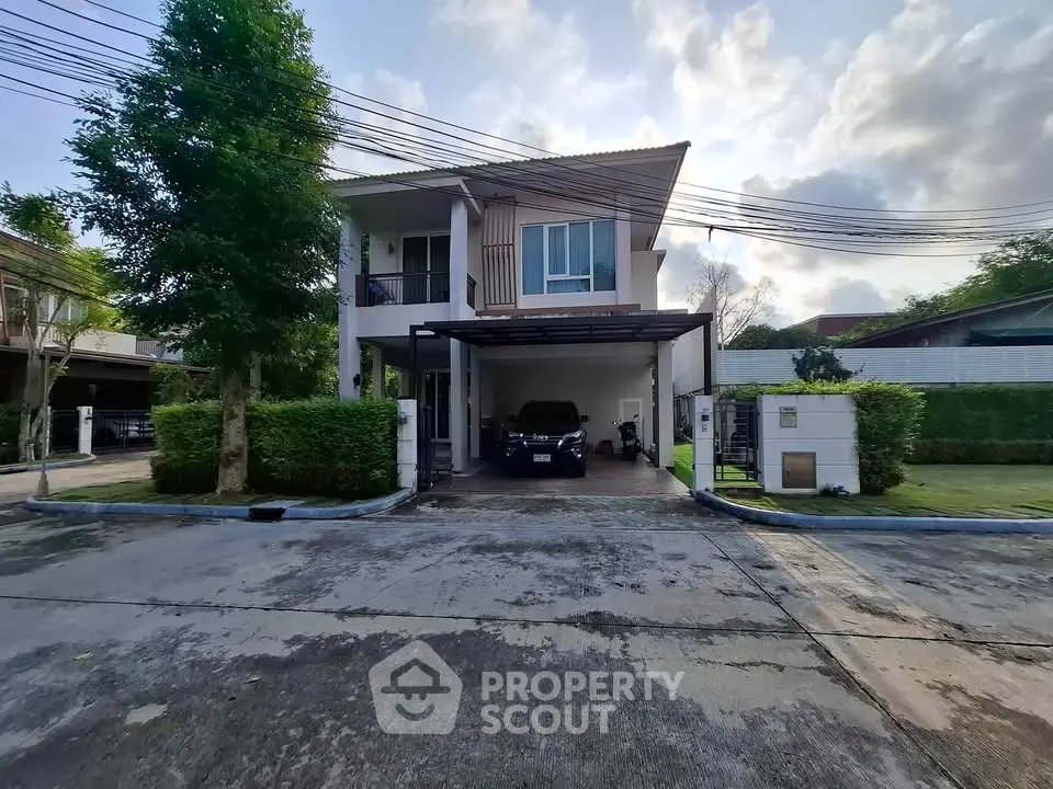 Modern two-story house with carport and lush greenery in a suburban neighborhood.