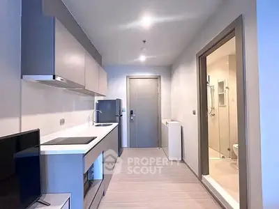 Modern kitchen with sleek cabinetry and adjacent bathroom in a compact apartment layout.