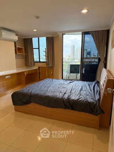Spacious bedroom with city view and modern furnishings in high-rise apartment.