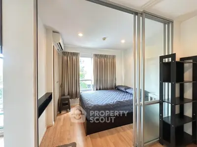 Modern bedroom with glass partition and cozy decor in urban apartment.