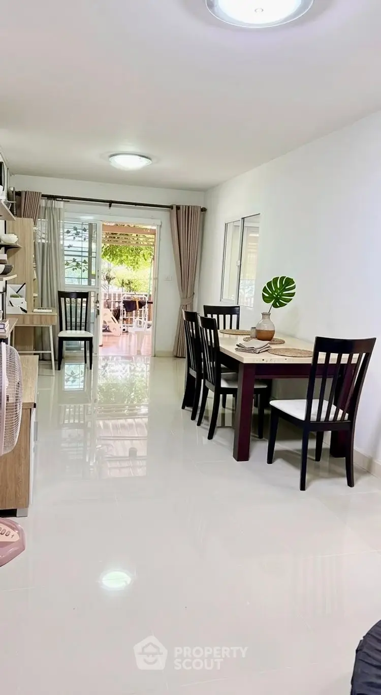 Spacious living room with dining area and large windows offering natural light and garden view.