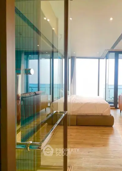 Luxurious bedroom with floor-to-ceiling windows offering stunning ocean views and modern decor.