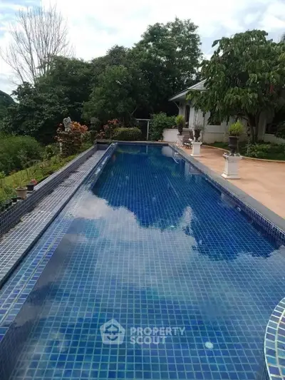 Luxurious outdoor pool with serene garden view, perfect for relaxation and leisure.