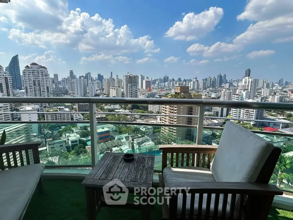 Stunning cityscape view from a high-rise balcony with cozy seating area.