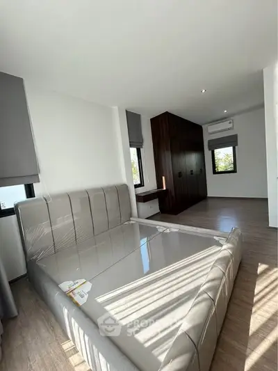 Modern bedroom with sleek design and natural light, featuring a stylish bed and built-in wardrobe.