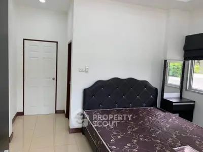 Spacious bedroom with large window and elegant bed in modern apartment.